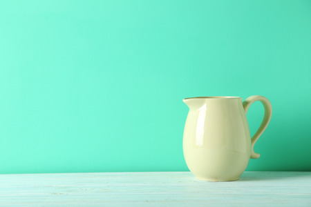 Beige jug on a green wooden tableの写真素材
