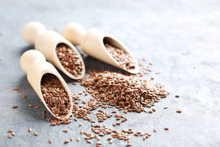 Brown flax seeds on grey wooden tableの写真素材