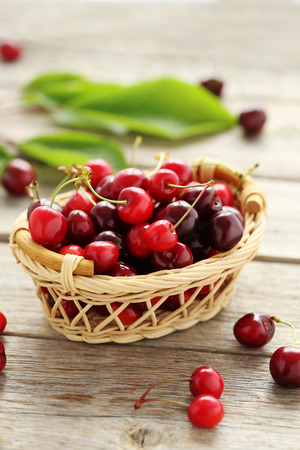 Ripe cherries in basket on a grey wooden tableの写真素材