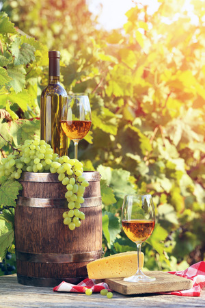 Wine in glasses with bunch of grape and cheese on wooden tableの写真素材