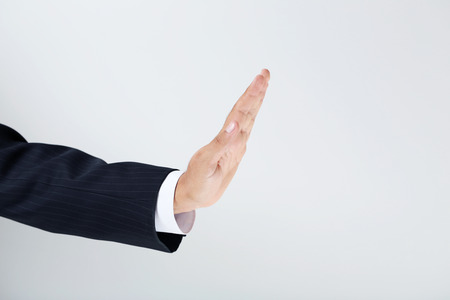 Businessman gesturing with his hand on grey backgroundの写真素材