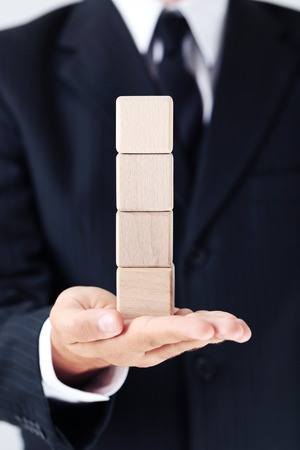Businessman holding wooden cubes in his handの写真素材