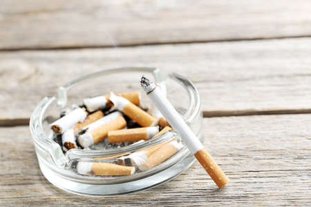 Cigarette with ash on grey wooden tableの写真素材