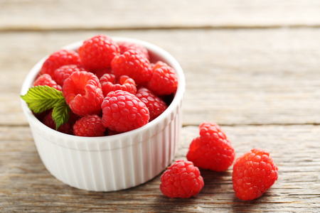 Red raspberries in bowl on a grey wooden tableの写真素材