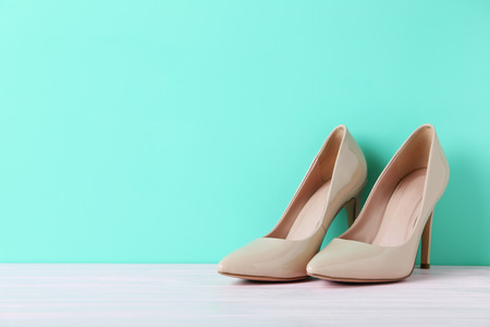 Pair of beige women's high-heeled shoes on wooden tableの写真素材