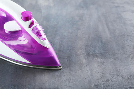 Electric iron on a grey tableの写真素材