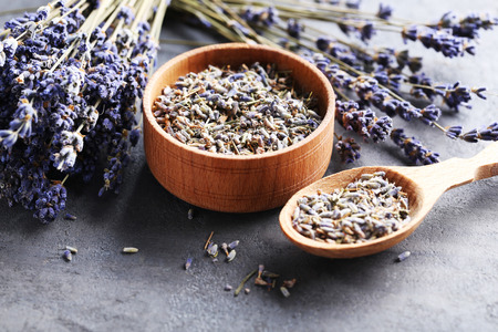 Lavender flowers in bowl and spoon on grey tableの写真素材