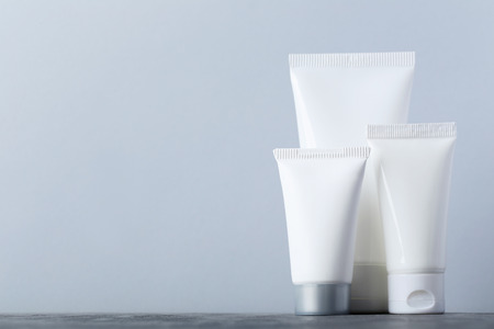 White cosmetic bottles on a grey tableの写真素材