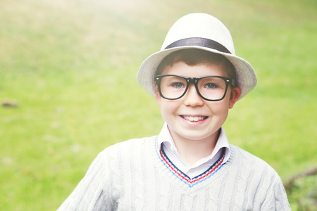 Portrait of young boy with eyeglasses and hat in the parkの写真素材