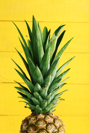 Ripe pineapple on a yellow wooden background