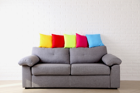 Colorful pillows on grey sofa on a brick wall backgroundの写真素材