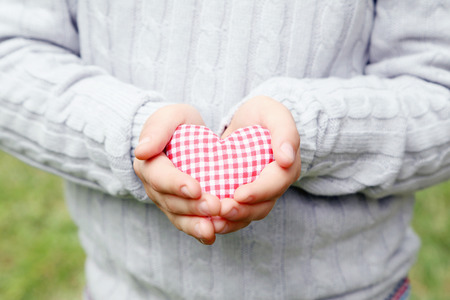 Child hand holding red heartの写真素材