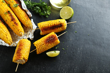 Tasty grilled corn on black wooden tableの写真素材