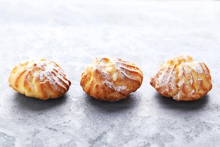 Homemade profiteroles with cream on grey wooden table