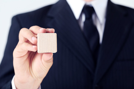 Businessman holding wooden cube in his handの写真素材