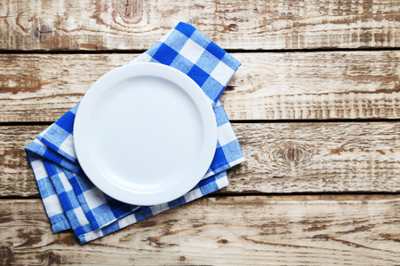 Empty plate with napkin on brown wooden tableの写真素材