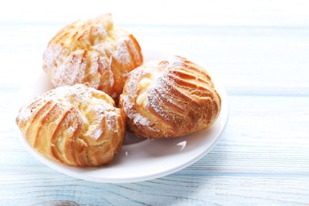 Homemade profiteroles with cream on white wooden table