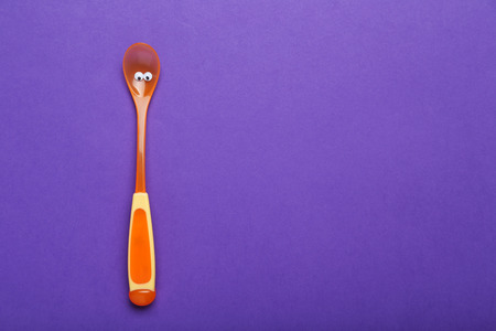 Plastic spoon with googly eyes on a purple backgroundの写真素材