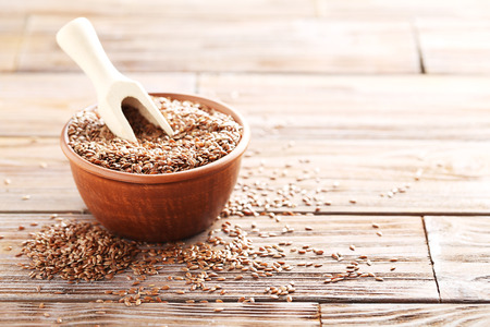 Brown flax seeds on a wooden tableの写真素材