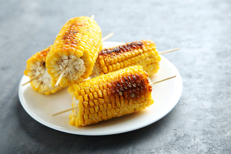 Tasty grilled corn on grey wooden table