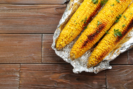 Tasty grilled corn on brown wooden tableの写真素材
