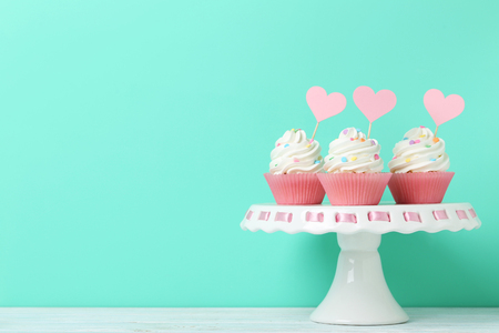 Tasty cupcakes on cake stand on green backgroundの写真素材
