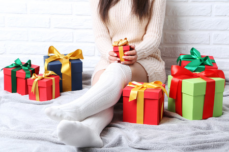 Woman with gift boxes sitting on grey plaid