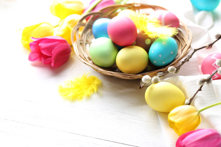 Easter eggs with tulips on a white wooden tableの写真素材