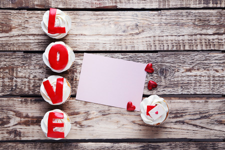 Tasty cupcakes with sheet of blank paper on a grey wooden tableの写真素材