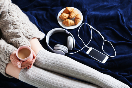 Woman with cup of coffee sitting on the bedの写真素材