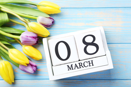 Bouquet of tulips with cube calendar on blue wooden table