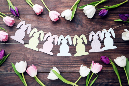 Bouquet of tulips with handmade easter rabbits on brown wooden table