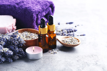 Lavender oil with soap and flowers on grey tableの写真素材