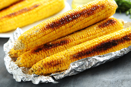 Tasty grilled corn on grey wooden table