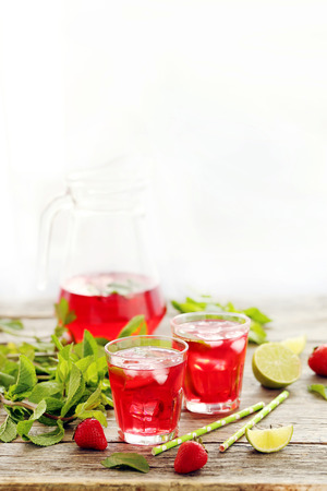 Fresh strawberry drink in glass with lime on wooden tableの写真素材