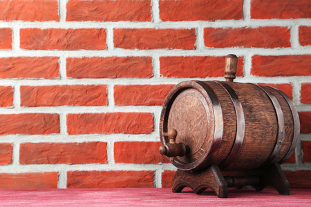 Wooden barrel with iron rings on brick wall background
