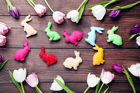 Bouquet of tulips with handmade easter rabbits on brown wooden tableの写真素材