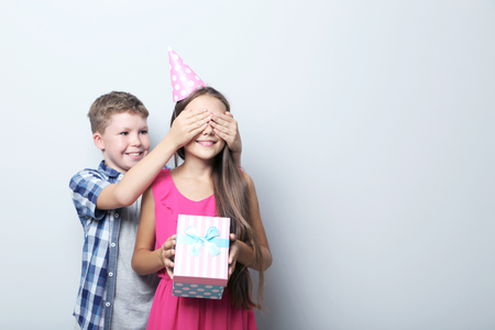 Boy covering eyes of girl, holding gift boxの写真素材