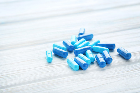 Heap of blue pills capsule on wooden tableの写真素材