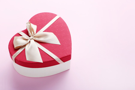 Heart gift box with ribbon on pink backgroundの写真素材