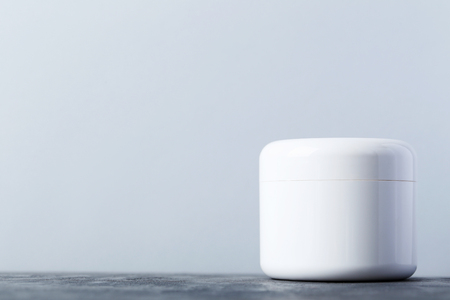 White cosmetic bottle on a grey tableの写真素材