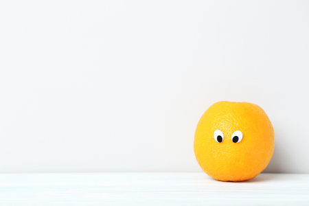 Ripe orange with googly eyes on grey backgroundの写真素材