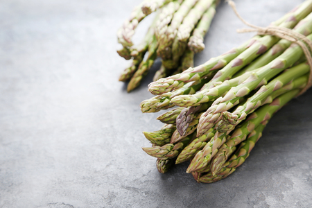 Heap of green asparagus on grey wooden tableの写真素材