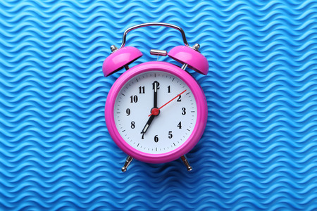 Pink alarm clock on blue background