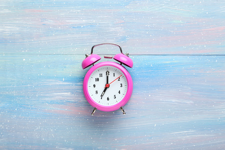 Pink alarm clock on blue wooden table