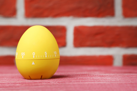 Yellow egg timer on a brick wall backgroundの写真素材
