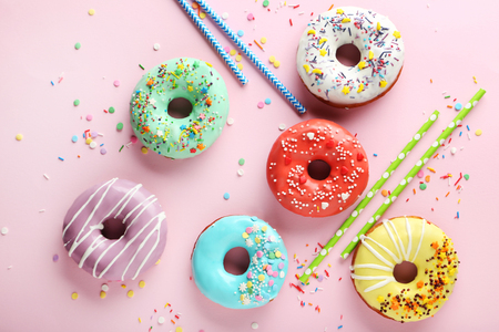 Tasty donuts with sprinkles on pink paper backgroundの写真素材