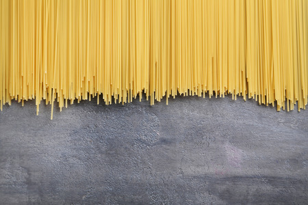 Bunch of spaghetti pasta on grey wooden tableの写真素材