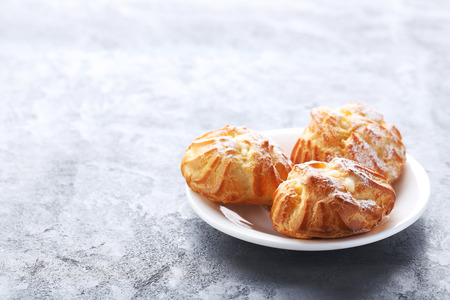 Homemade profiteroles with cream on grey wooden table