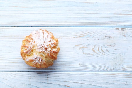 Homemade profiterole with cream on white wooden table